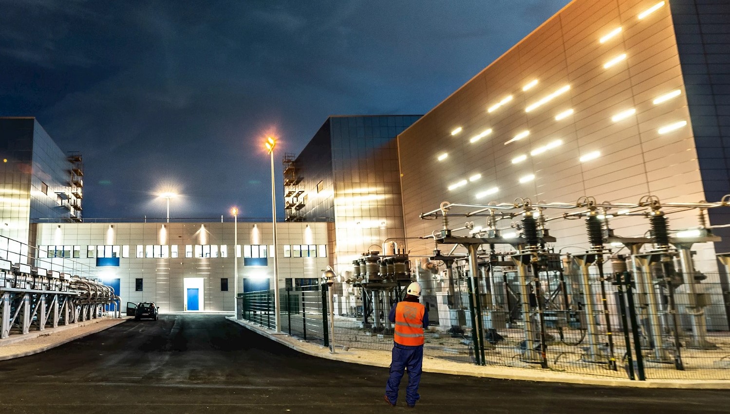 Worker at a lit up grid station at night