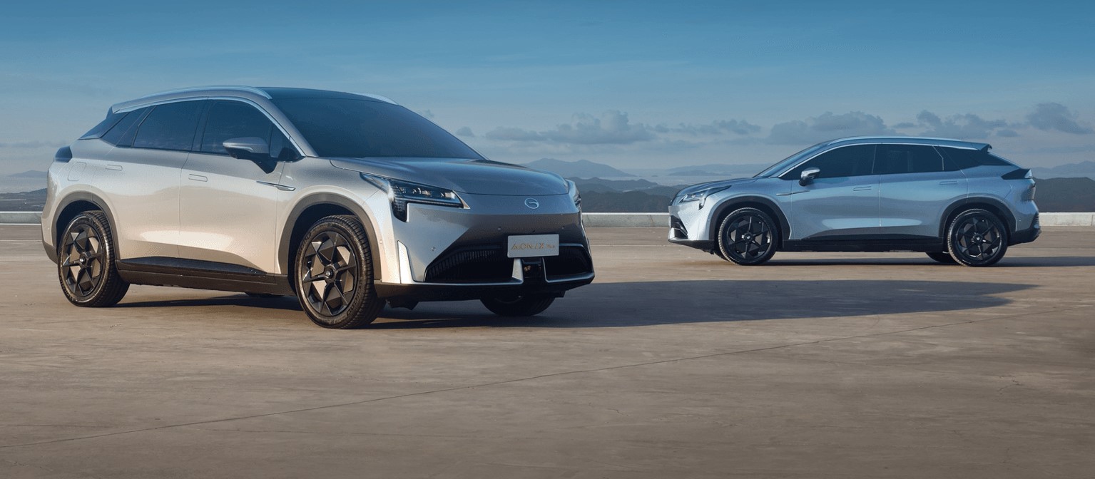 Two silver Aion LX cars parked on a concrete expanse