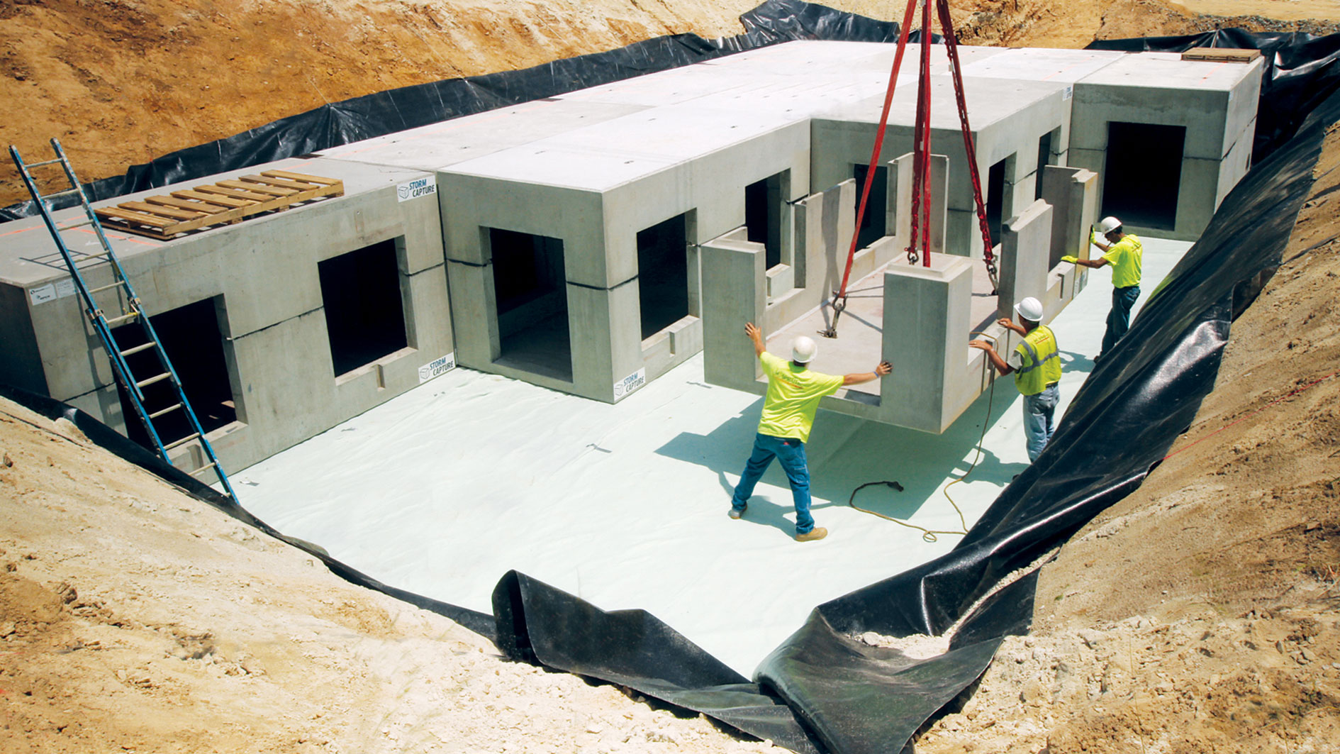 Workmen installing a concrete storm water capture system in a big pit