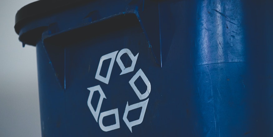 closeup of a recycling logo on a blue bin