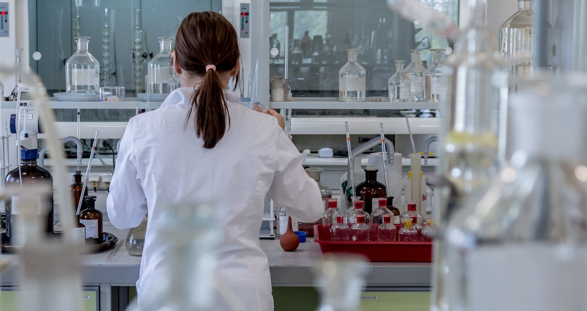 Rear view of woman scientist in a laboratory surrounded by beakers