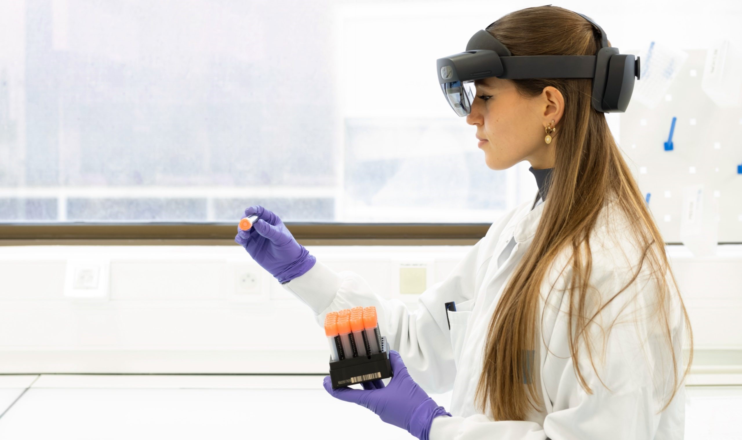 Scientist wearing AR visor and gloves, handling test tube samples