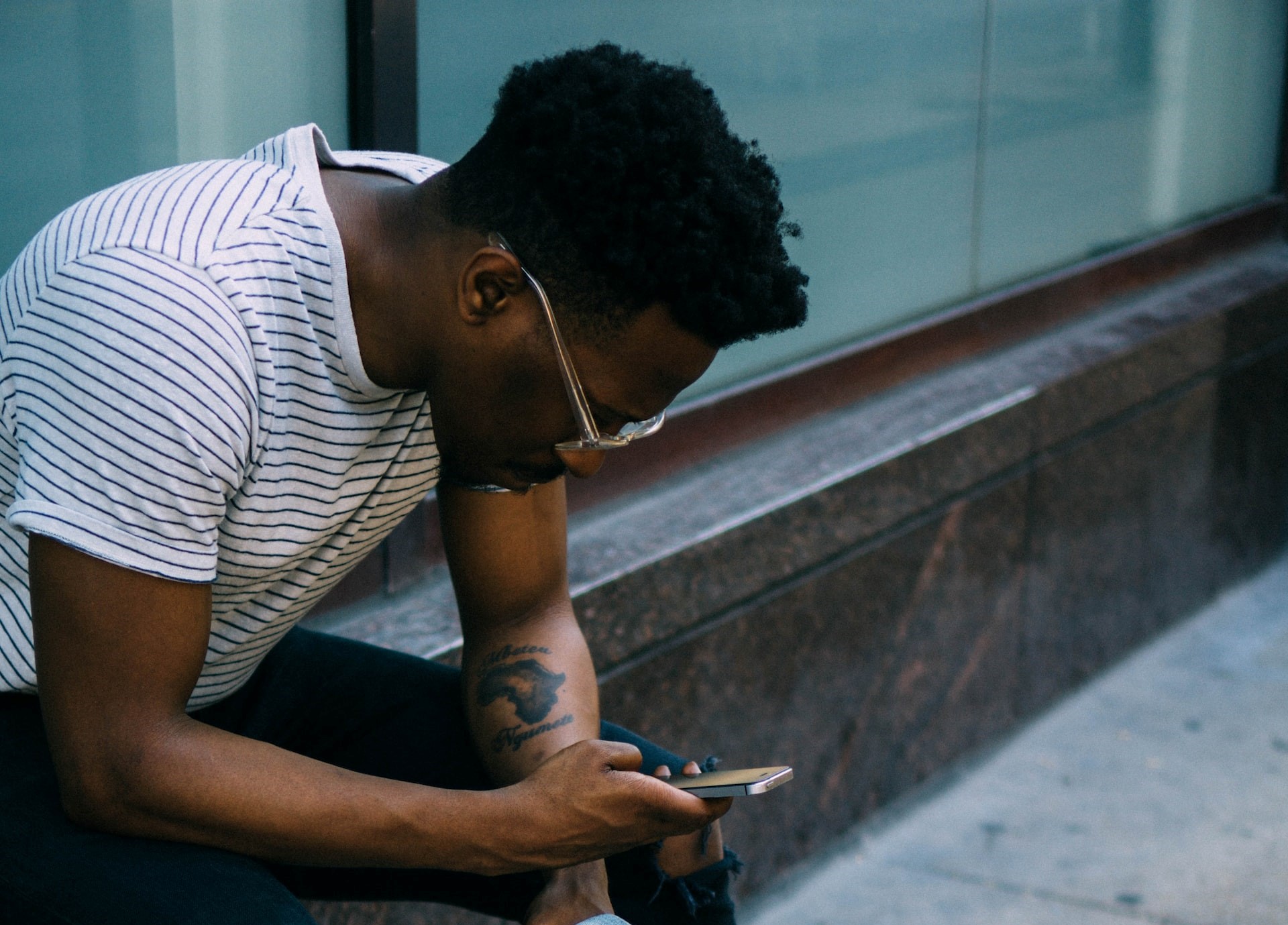 Man sitting against window looking at smartphone