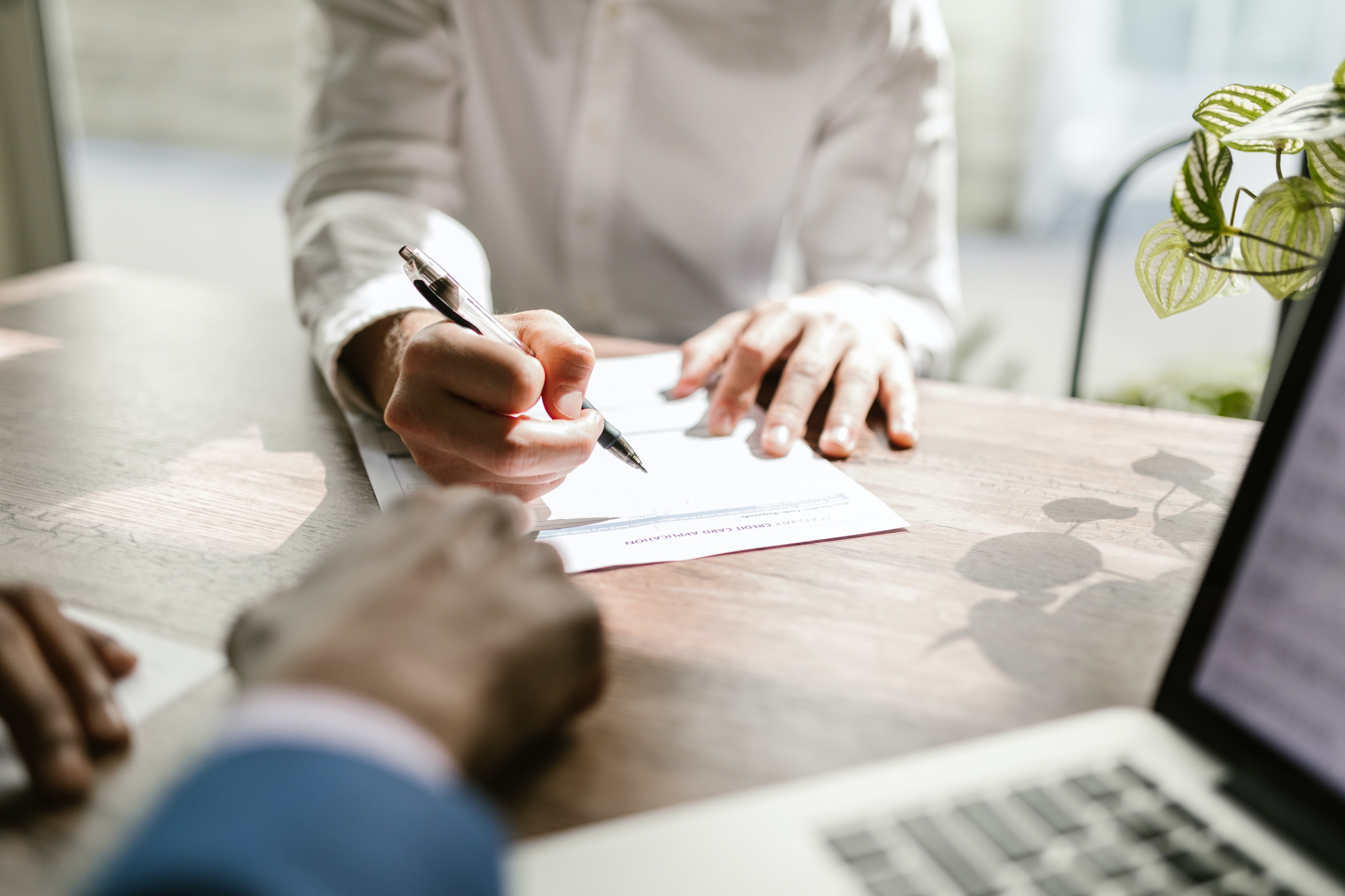 a closeup of two people signing an agreement on a table