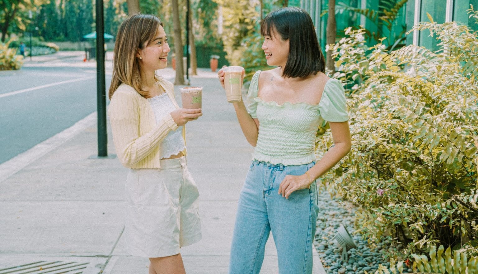 Women looking at each other holding Pickup coffee cups