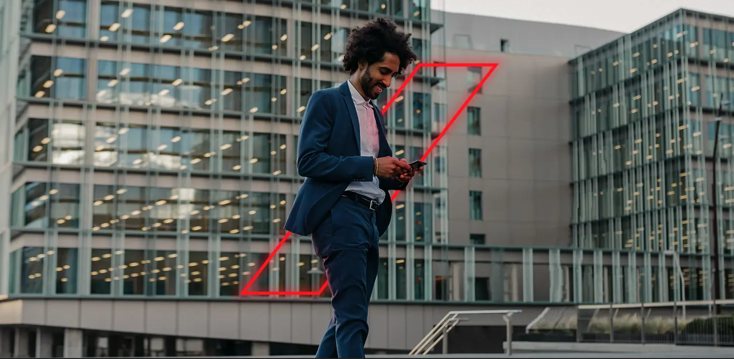 Man in suit looking at phone outside offices, in front of red diagonal framed dash