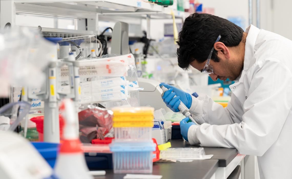 Lab technician studying sample in crowded laboratory