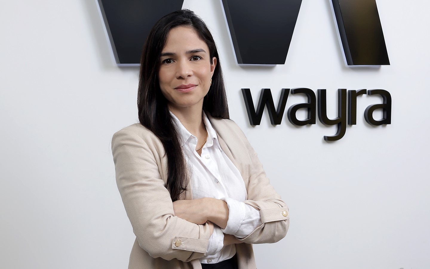 Gabriela Toribio crossing her arms in front of a Wayra sign