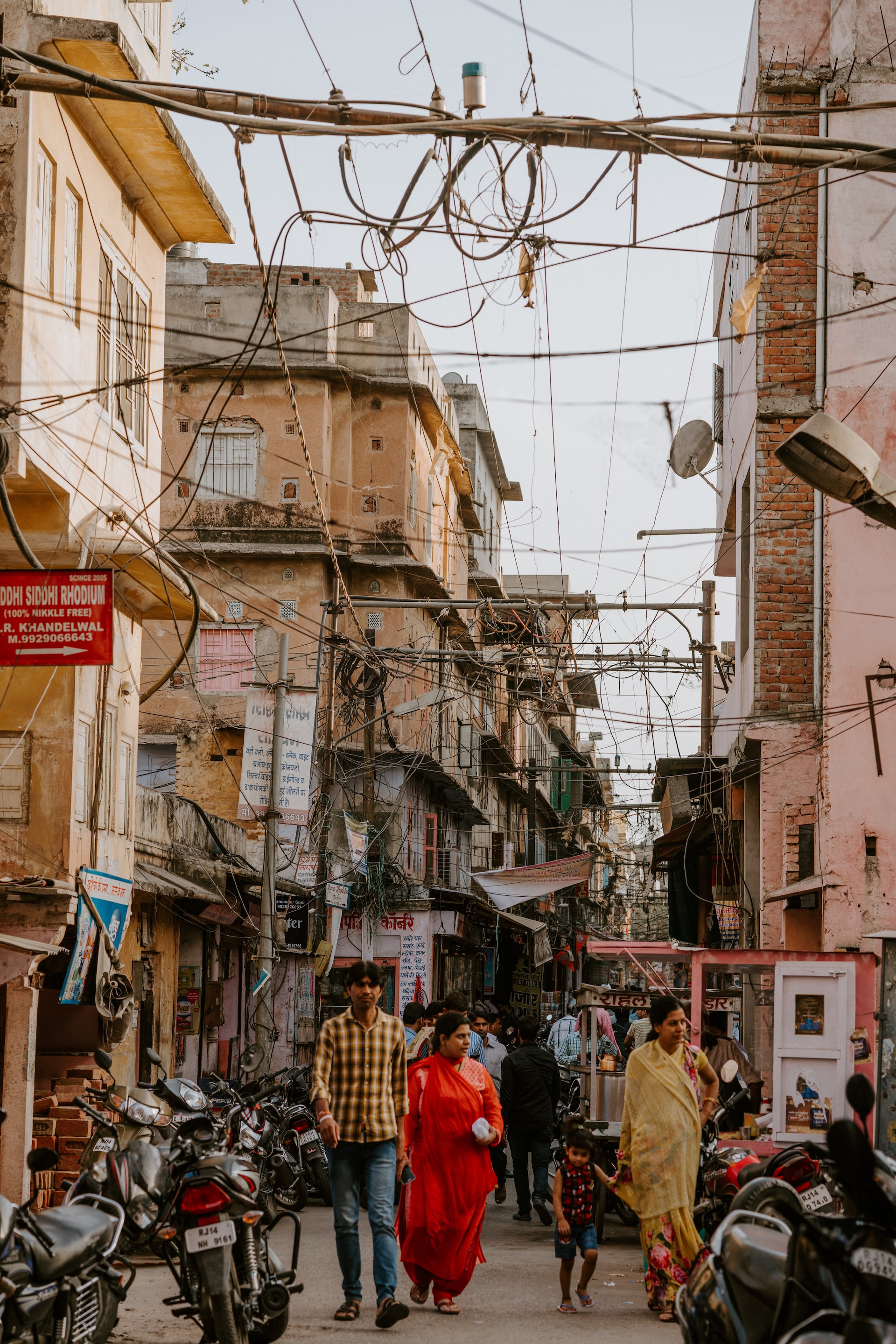 Indian family walk down a street in Jaipur surrounded by motorcycles