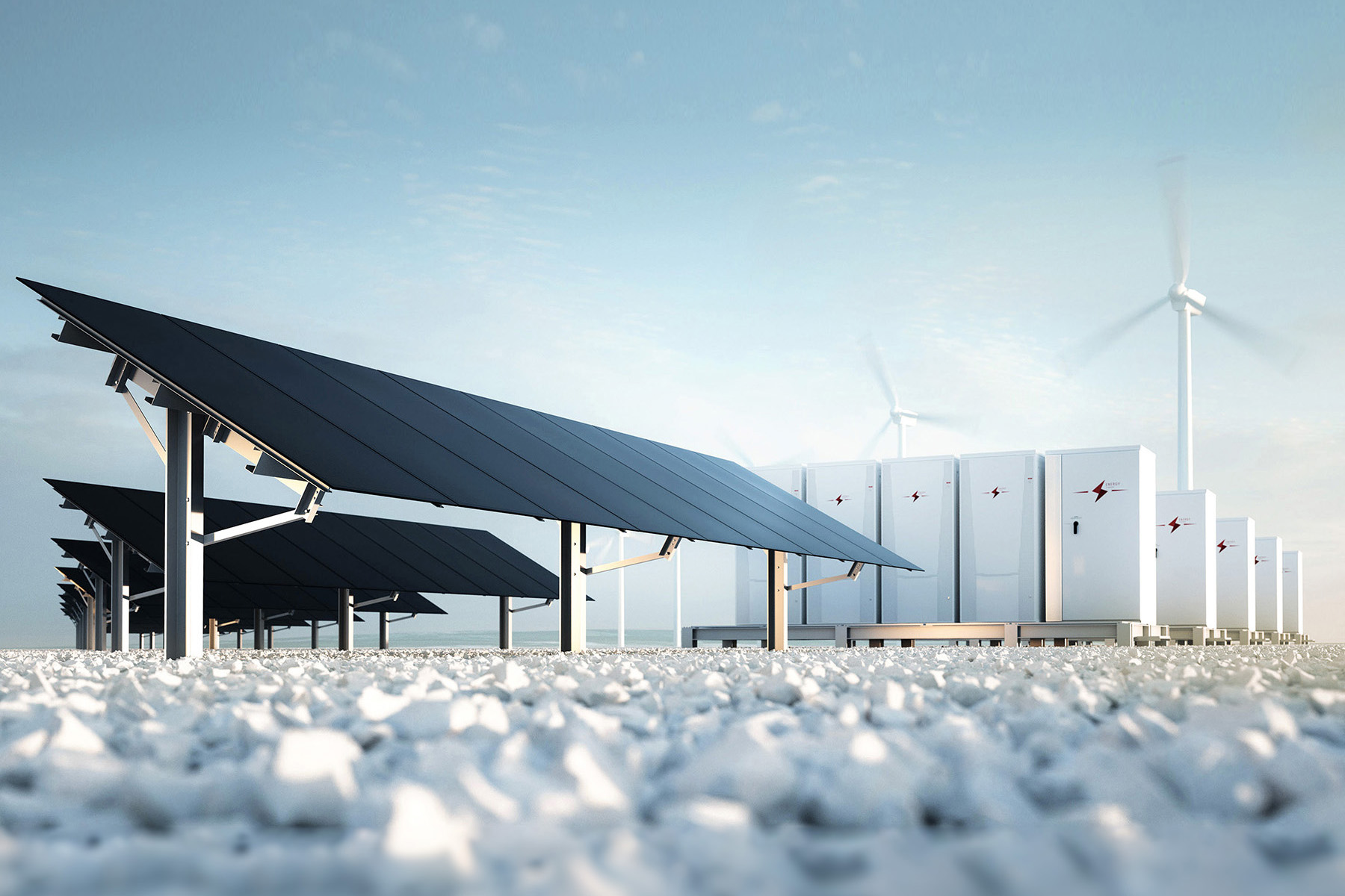 Solar panels, battery storage units and wind turbines on a white stone beach