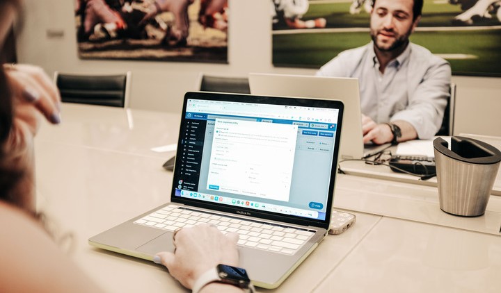 Woman at desk looking at laptop screen facing man doing the same