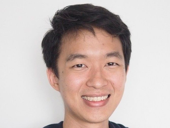 Headshot of Chris Sirise in black T-shirt against white-ish background