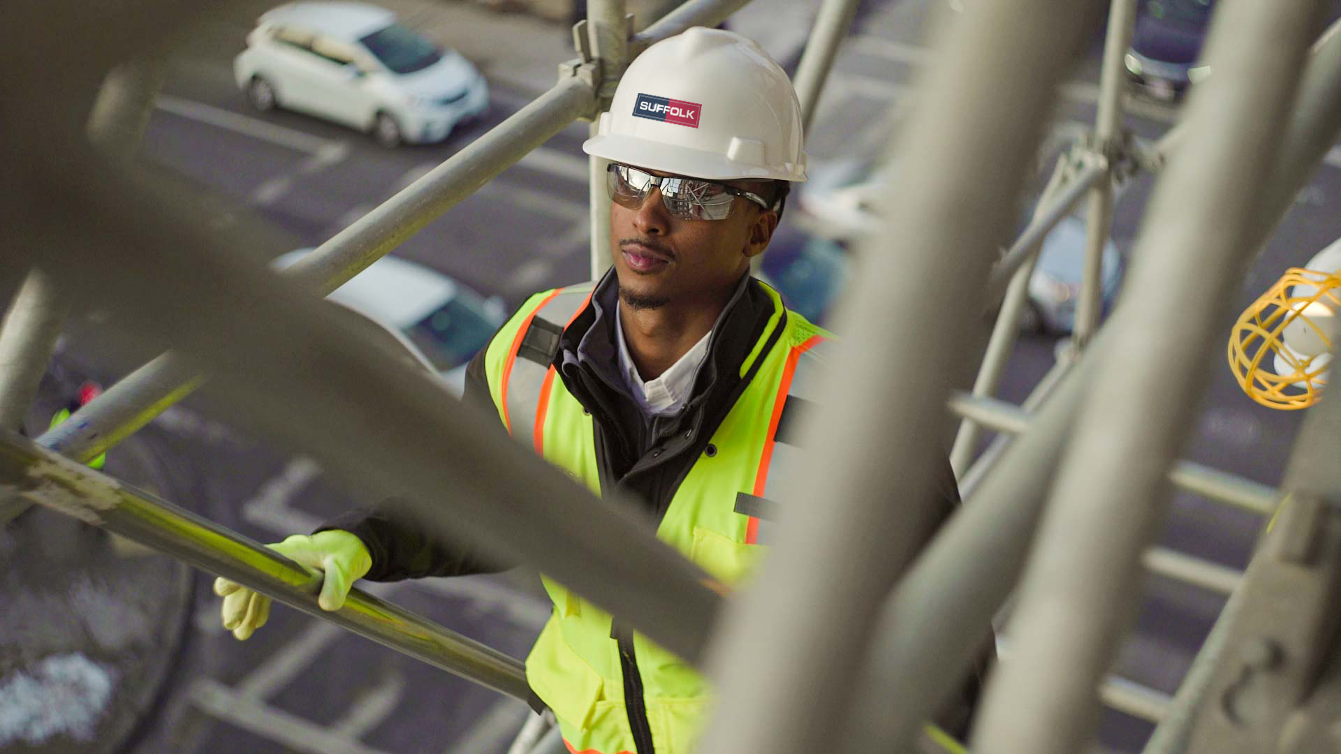 Construction worker in helmet and sunglasses walking down crane stairs