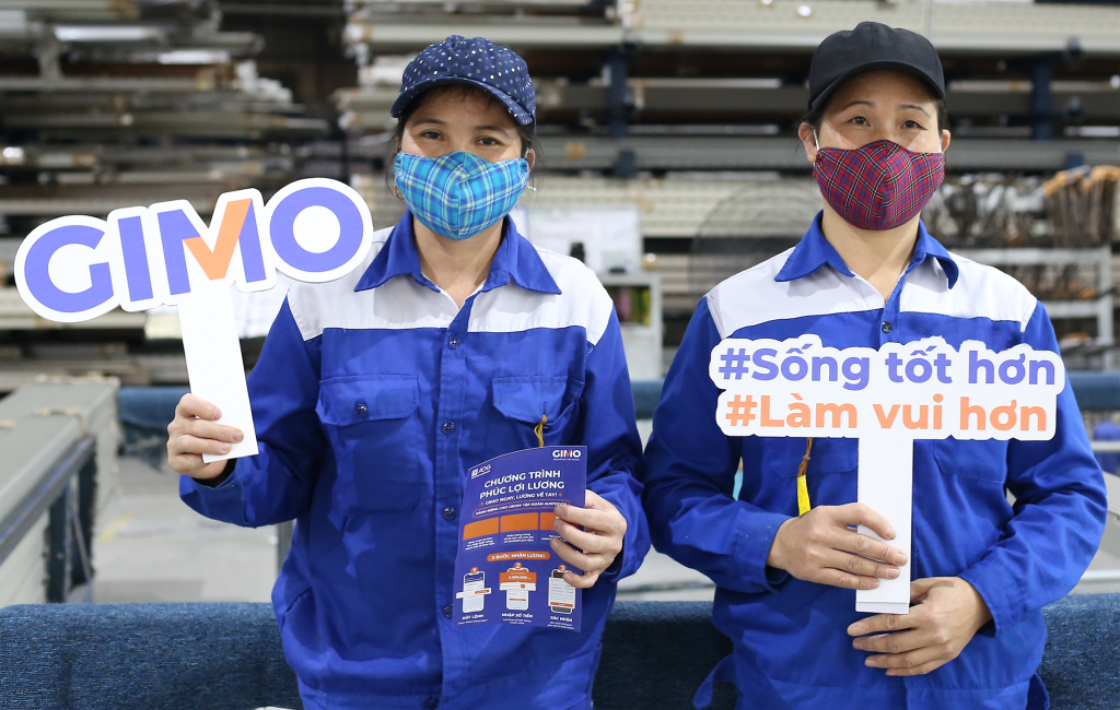 Gimo workers with signs showing the company name and hashtags in Vietnamese