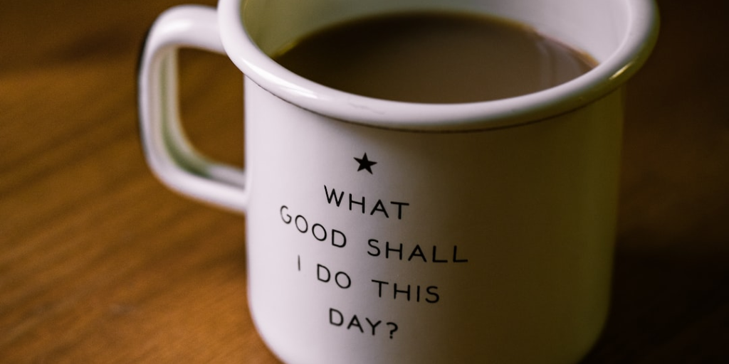 a white enamel coffee cup with the words “what good shall I do this day?" written on it in black sans serif letters