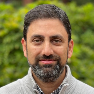 Headshot of Harsha Kapre in front of blurred tree background