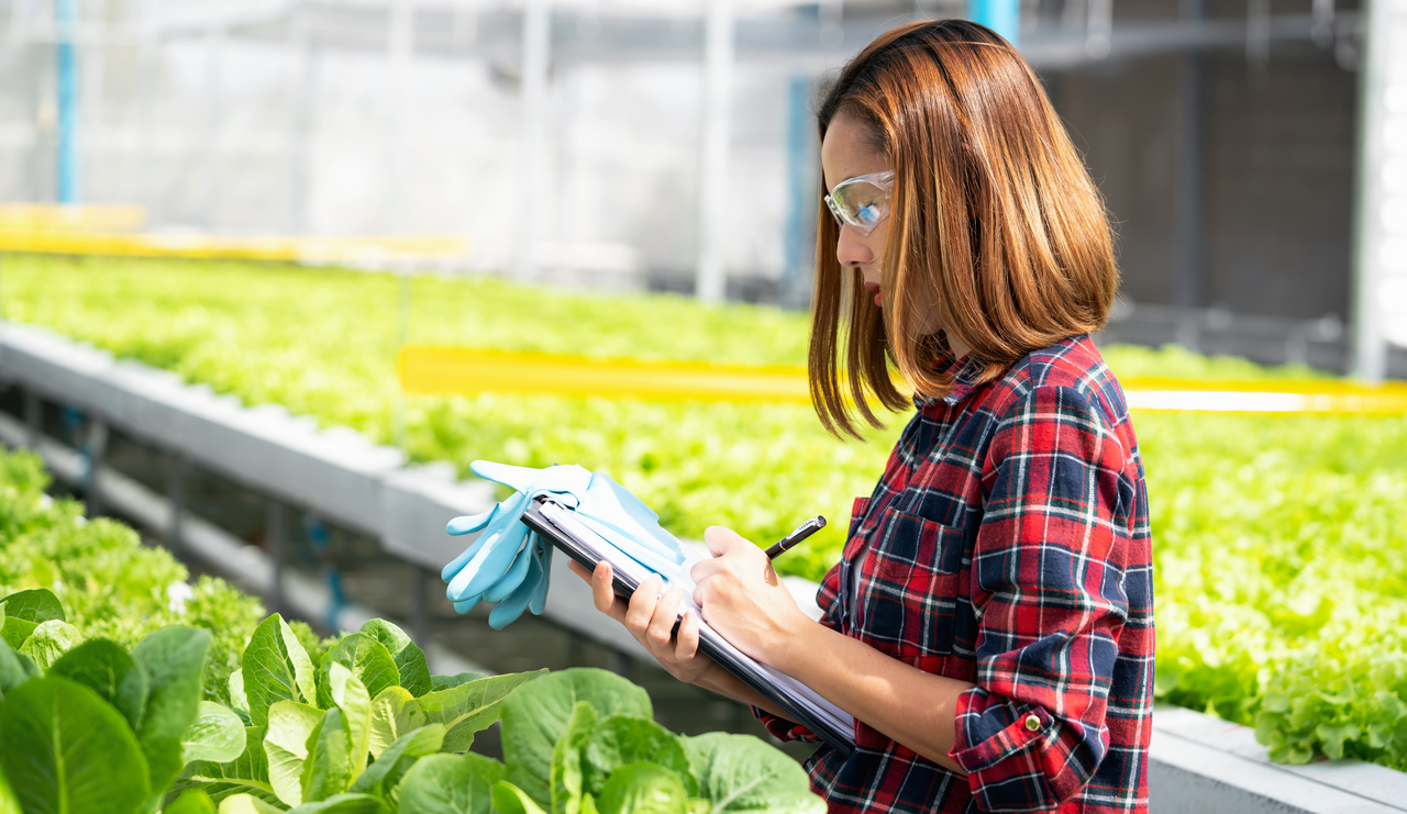 Agriculture worker in a greenhouse testing and recording data