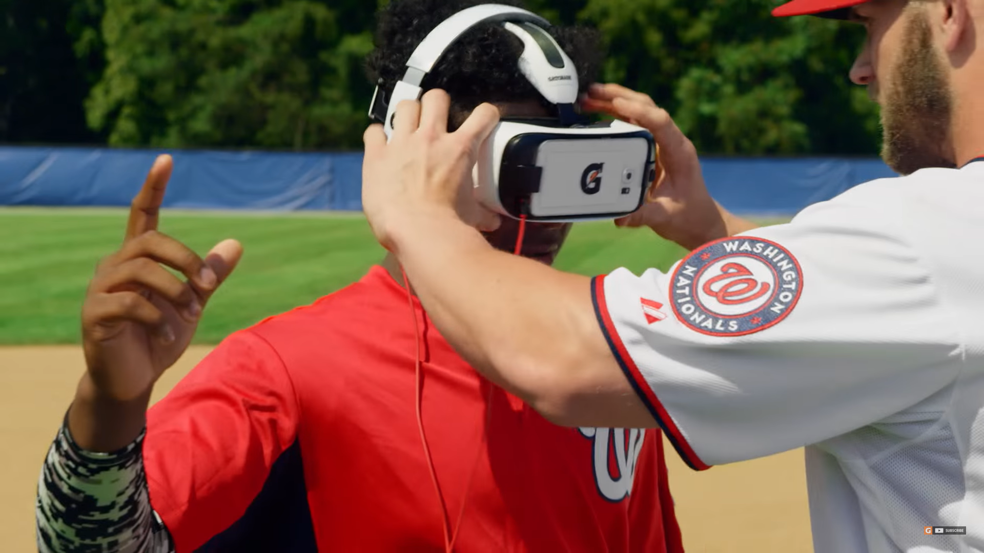 Baseball player in white holds VR headset worn by by baseball player in red