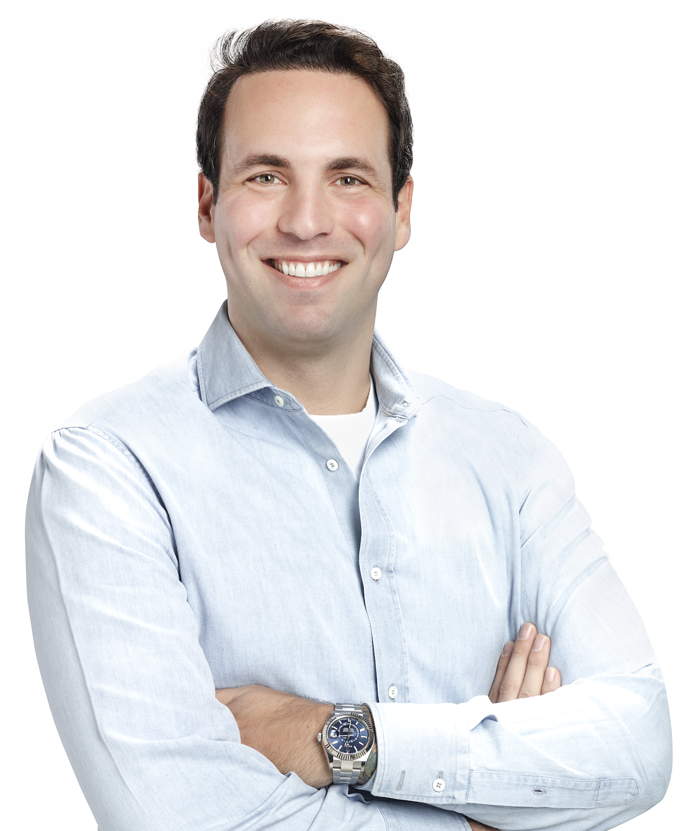 Headshot of Sinan Uzan crossing arms in pale blue shirt with white background