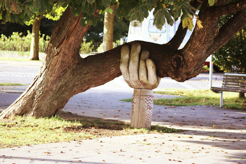 Metal hand propping up tree