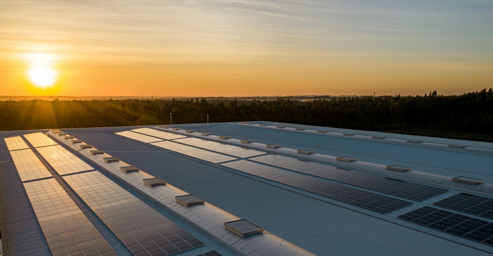 The sun sets over solar panels on a building rooftop