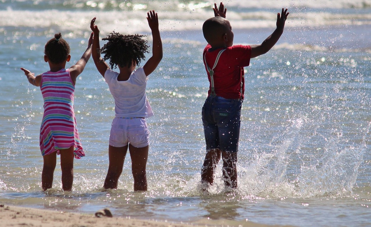 Three children play in the waves