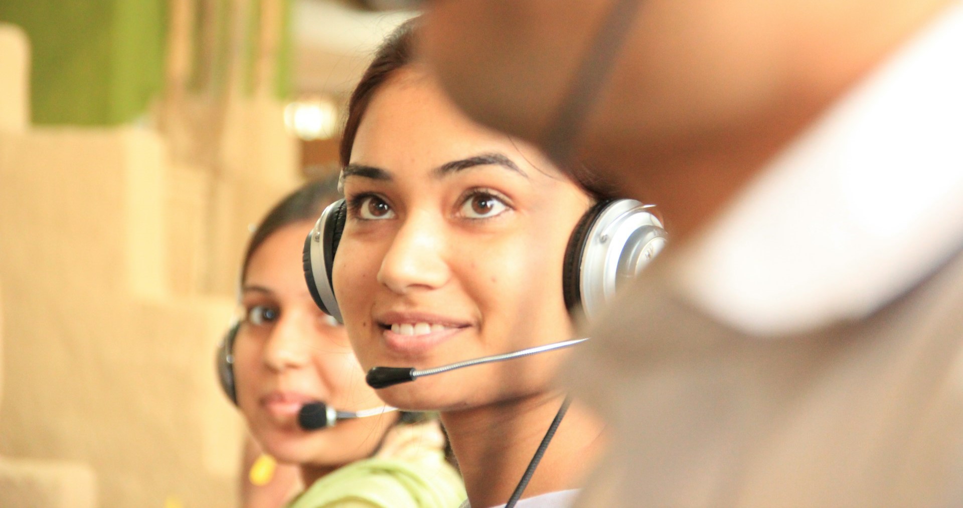 A row of call centre operators, with a woman operator close up