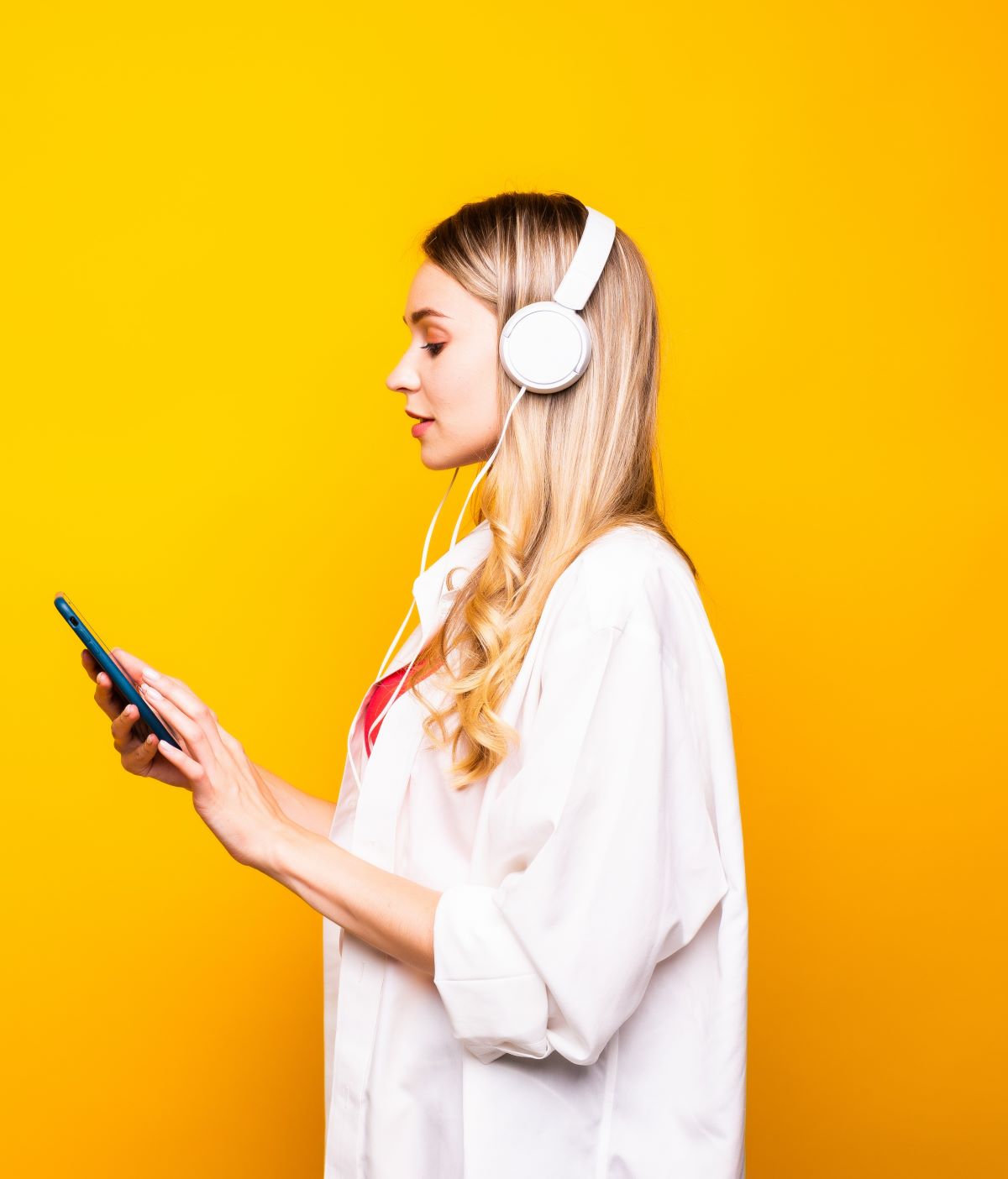 Woman wearing headphones looks at her phone