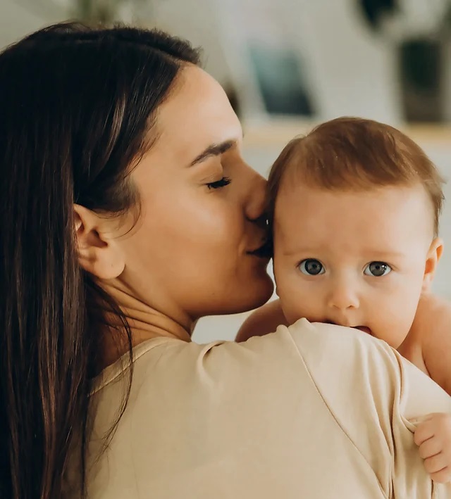 A mother holds and kisses her baby