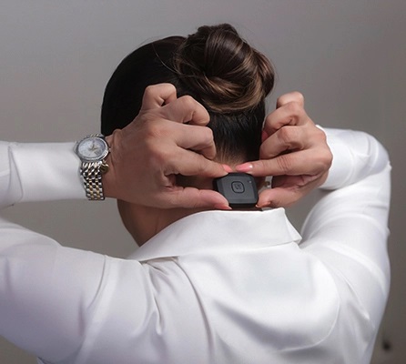 Woman sticking Unpause device to the back of her neck