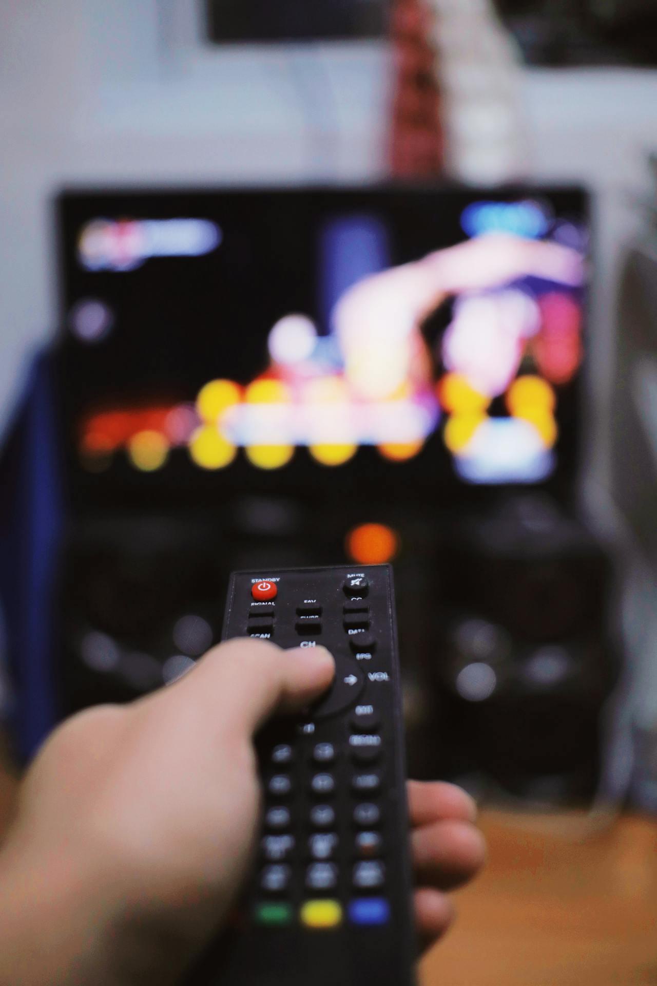 A hand pointing a remote control to a TV