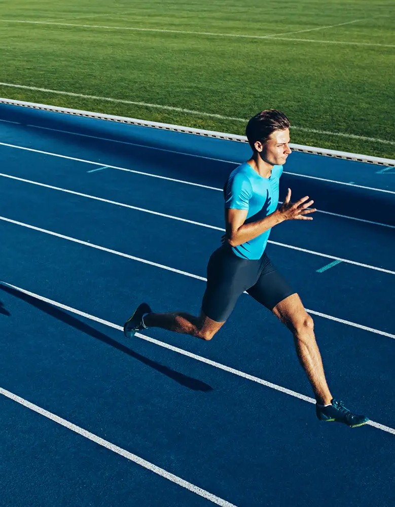 An athlete sprints down a blue track