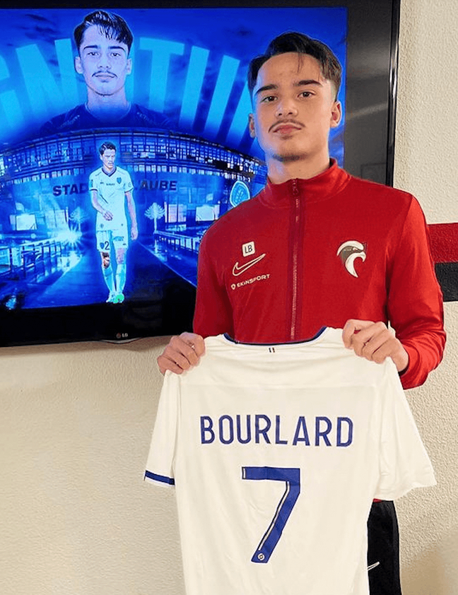 Liam Bourlard holding up a white and blue football shirt with his name on the back