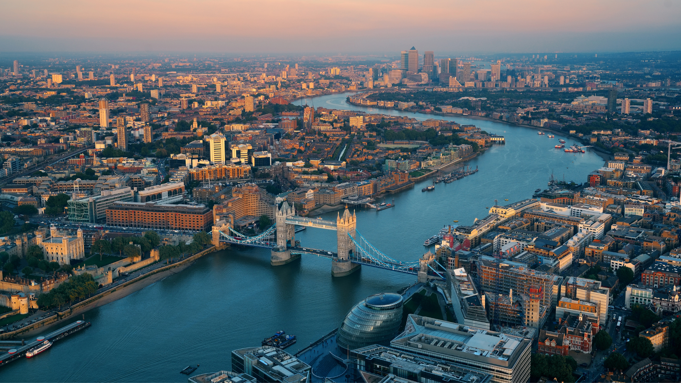 An aerial view of the Thames winding through London with Tower Bridge in the foreground
