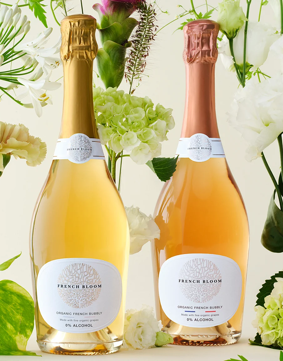 Two bottles of French Bloom sparkling wine in front of plant wallpaper