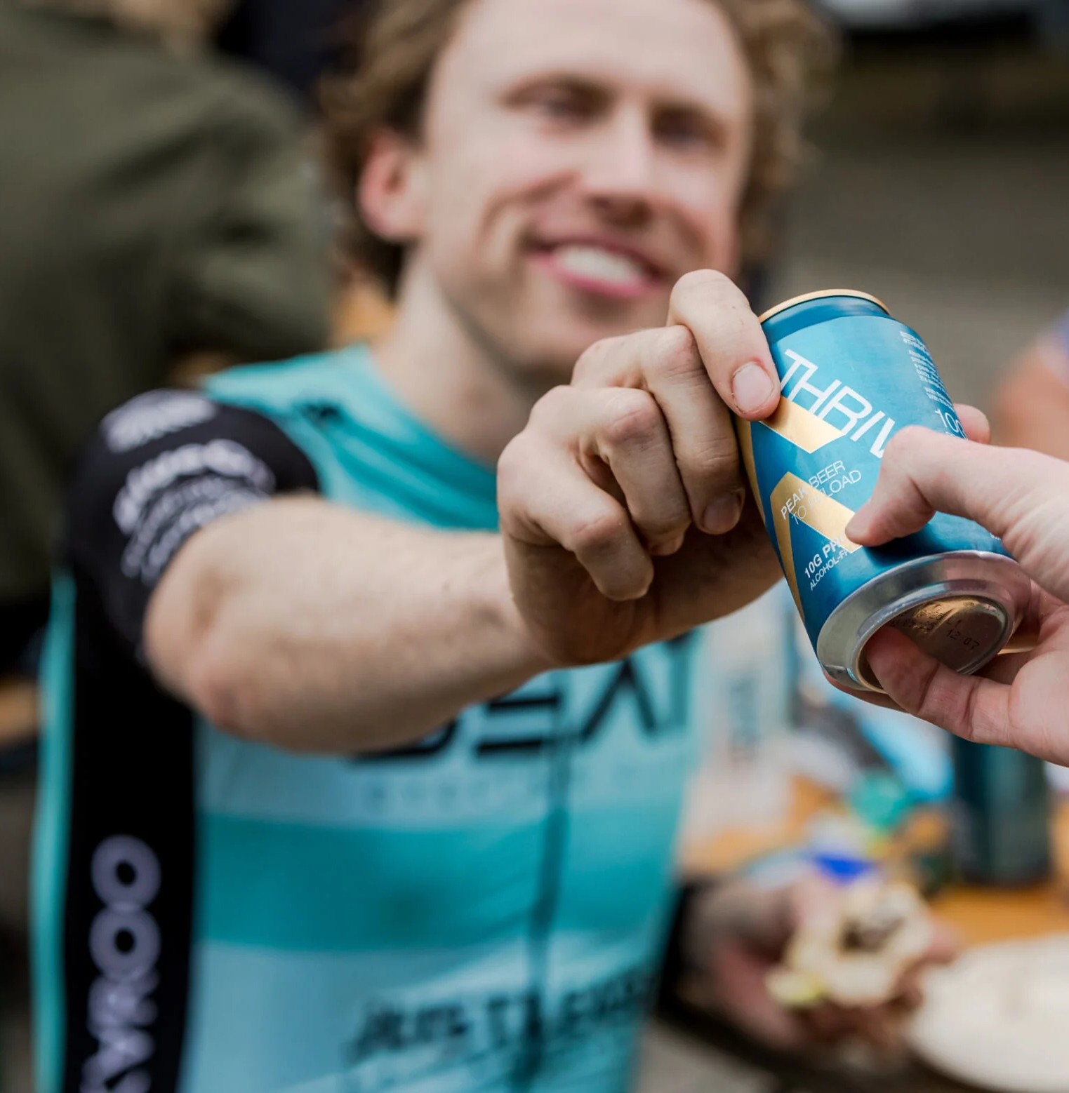 A cyclist being handed a can of Thrive beer