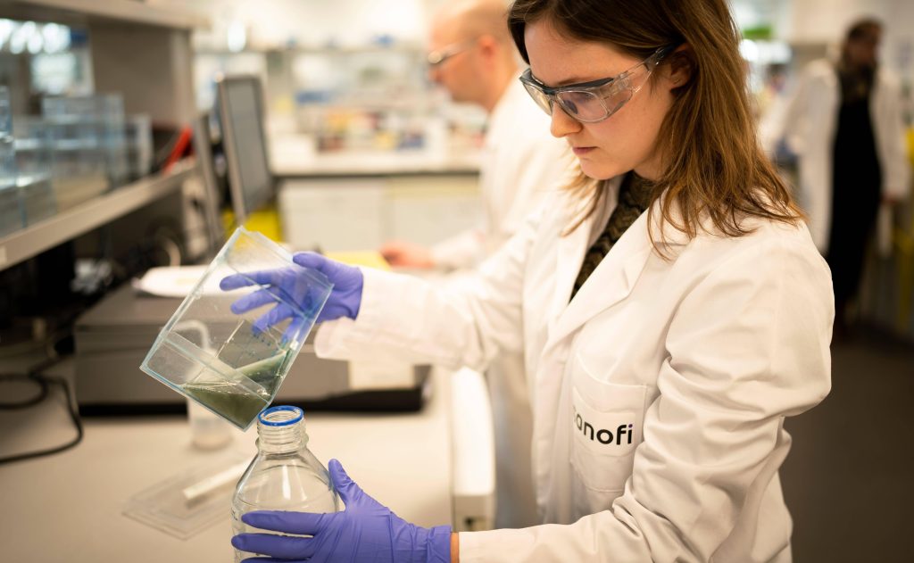 A Sanofi scientist pours liquid into a bottle