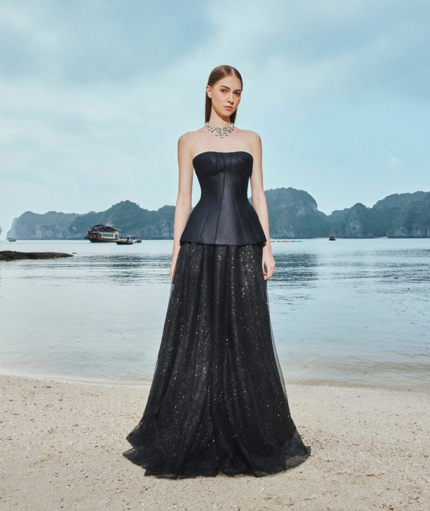 A woman in a black dress, posing on a beach