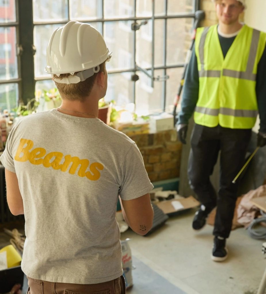 A workman in a Beams T-shirt greeting one in high-visibility clothing