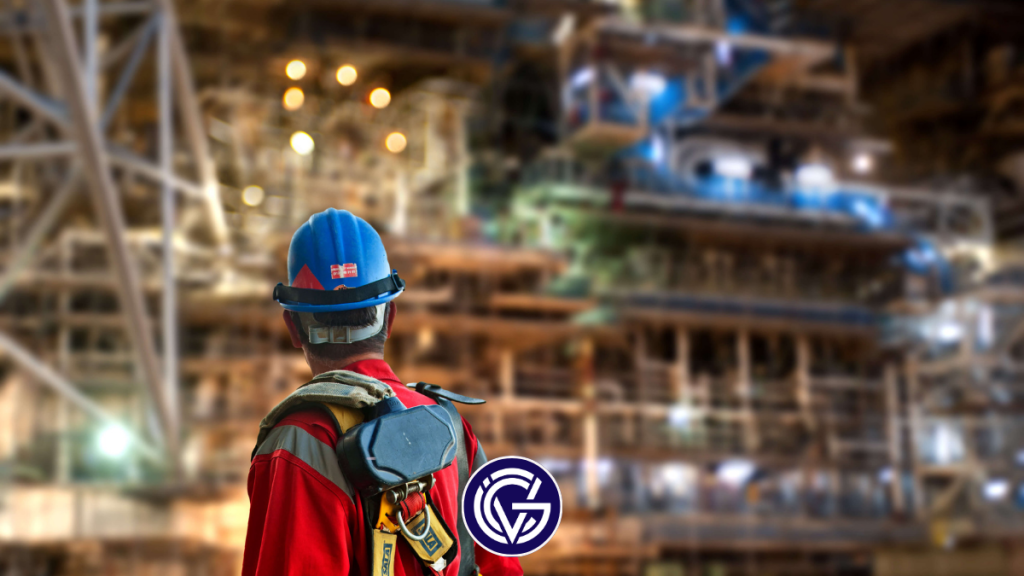 An industrial worker looks at an oil rig-like structure in the distance